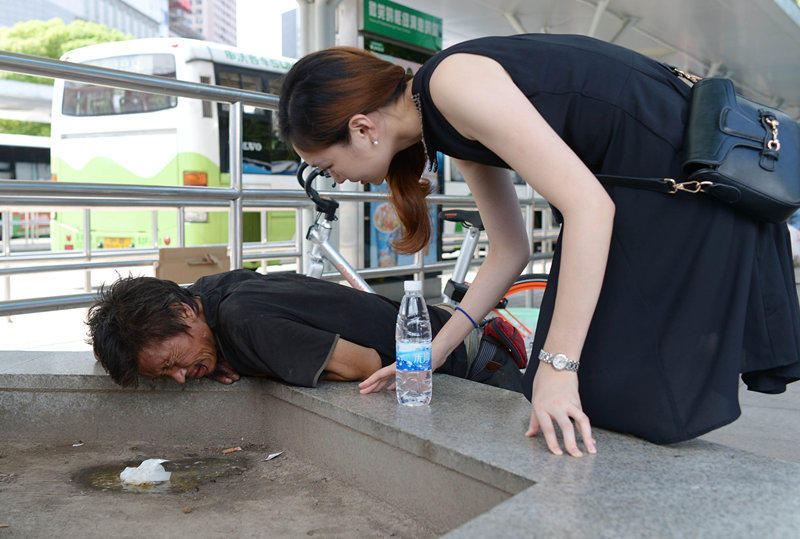 一流浪汉花坛边呕吐 陌生女孩为其买药